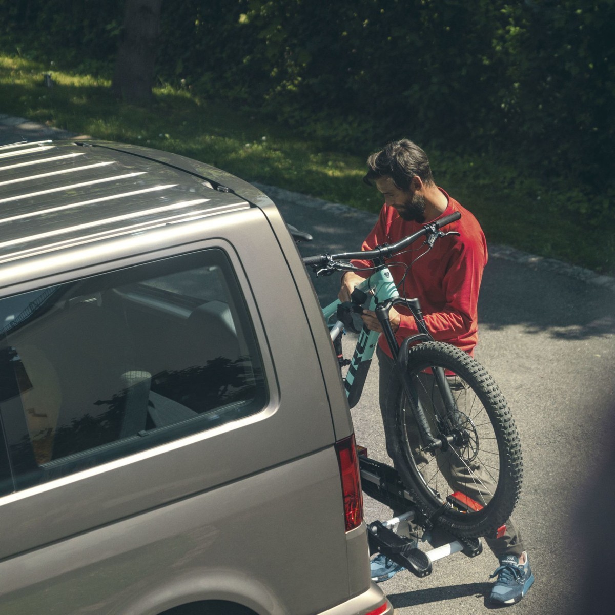 Uomo che carica una bicicletta nel portabici posteriore di un Volkswagen Veicolo Commerciale 